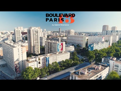 Sweeping urban vista of Paris's 13th arrondissement, showcasing modern residential buildings adorned with vibrant street art murals and green spaces under a clear blue sky, reflecting the city's artistic energy.