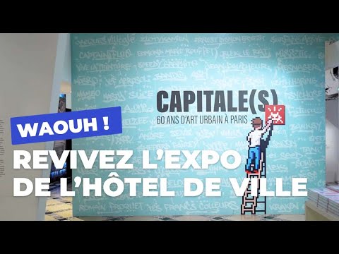 A vibrant blue-green exhibition wall, covered with names of iconic urban artists, features the bold title CAPITALE(S) - 60 ANS D'ART URBAIN À PARIS and a whimsical pixel art figure on a ladder affixing a red Space Invader, evoking the playful spirit of street art.