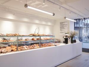 Bright, modern interior of Bäckerei Jung Central featuring long glass display cases abundant with fresh breads and pastries, a sleek white counter, and a coffee station, creating a clean and inviting atmosphere.