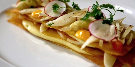 Vegetarian fine dining dish from Cookies Cream, featuring delicate radish slices, fresh herbs, and vibrant sauce spheres atop a golden, crispy base.