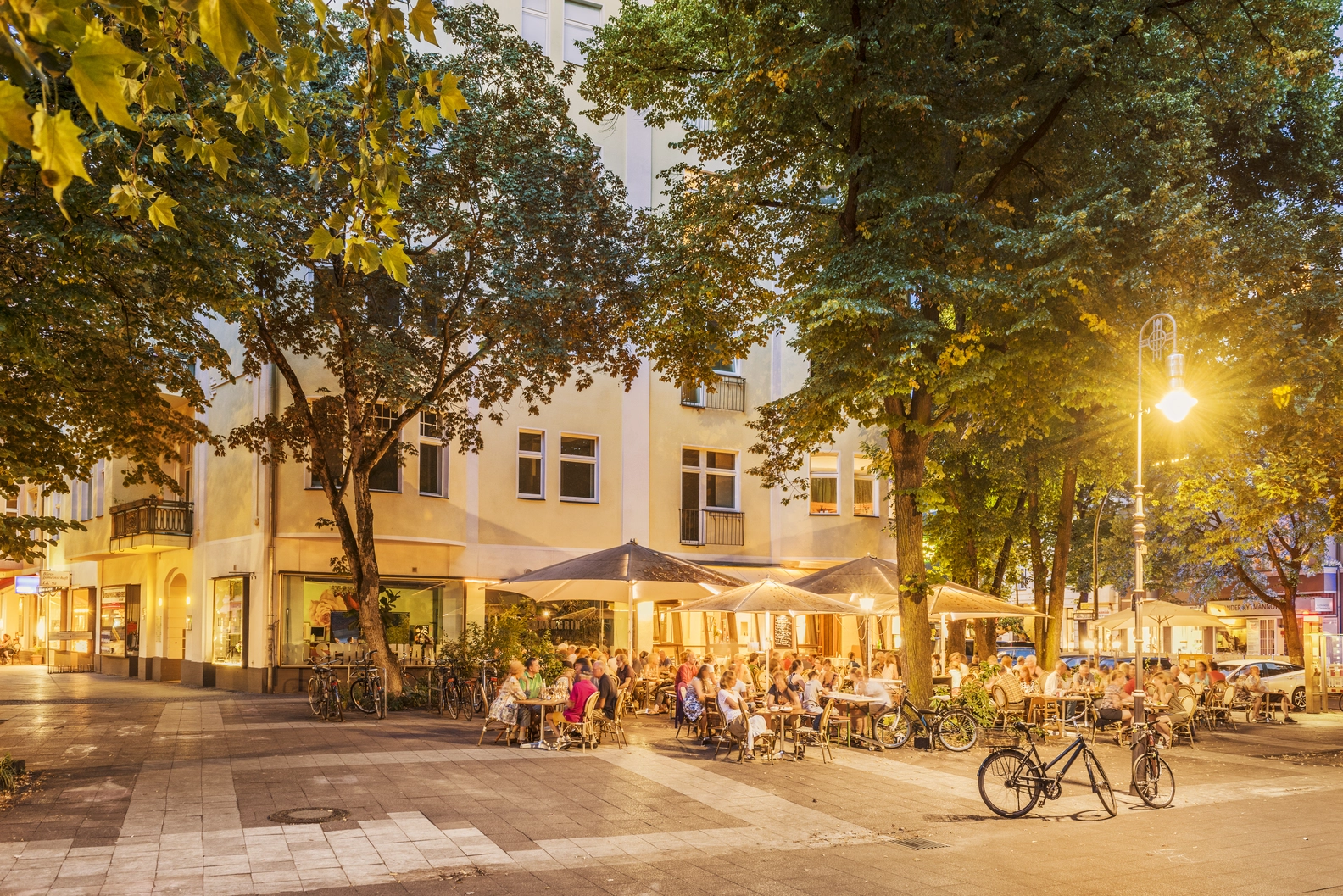Romantic evening outdoor dining at Cafe Weyers, featuring customers enjoying al fresco seating under warm lights and trees.