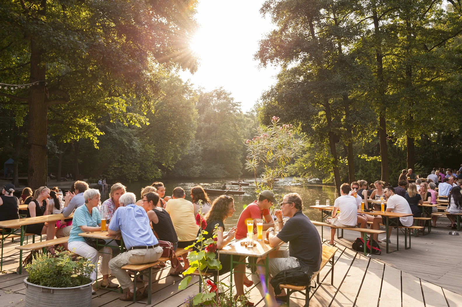 Sunny outdoor beer garden at Café am Neuen See, bustling with people enjoying drinks at lakeside tables.