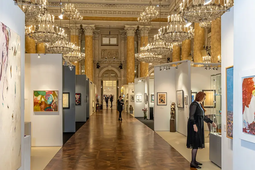 Grand hall adorned with crystal chandeliers showcasing an autumn art and antique exhibition, featuring diverse paintings, sculptures, and collectibles.