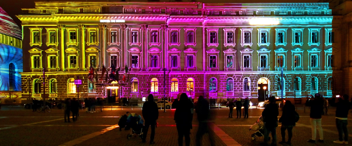 Hotel de Rome illuminated with vibrant yellow, pink, and blue light projections during the Berlin Festival of Lights tour.