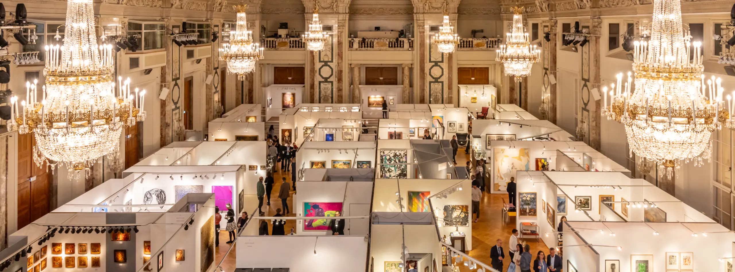 Vibrant autumn art exhibition in a majestic hall, showcasing diverse artworks, visitors, and opulent crystal chandeliers.