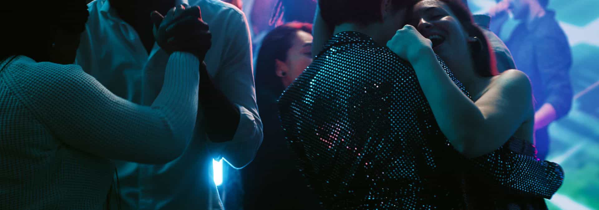 Dancers enjoying an energetic summer dance night at Grochowska, illuminated by vibrant blue and purple club lights.
