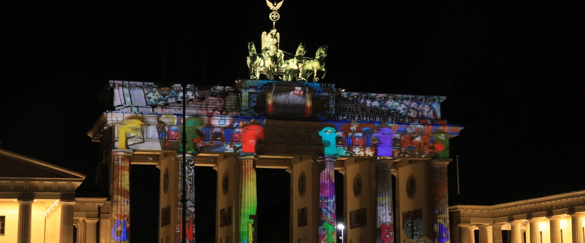 Brandenburg Gate vibrantly illuminated with colorful art projections during Berlin's Festival of Lights.