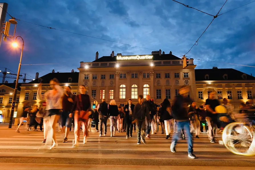 Illuminated MuseumsQuartier Vienna bustling with visitors attending the Long Night of Museums, an autumn art event.