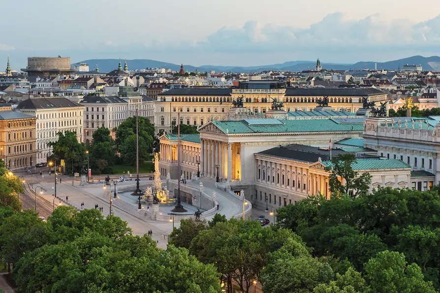 Vienna's majestic Austrian Parliament building and Pallas Athena Fountain along the historic Ringstrasse at dusk.